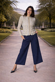 Modella che indossa la giacca GRACE con foglie in pelle su tulle, abbinata a pantaloni blu navy in un ambiente elegante.