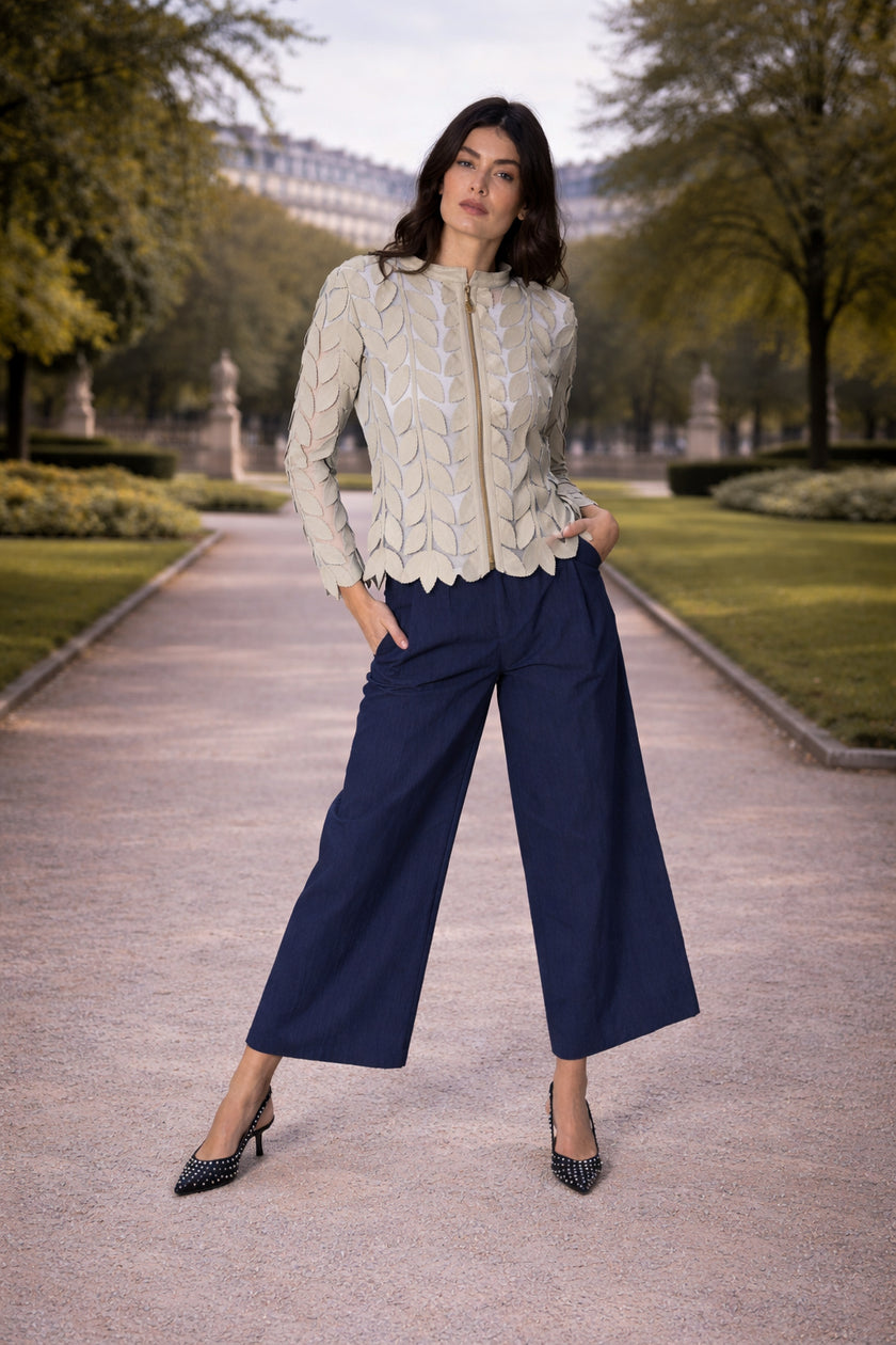Modella che indossa la giacca GRACE con foglie in pelle su tulle, abbinata a pantaloni blu navy in un ambiente elegante.