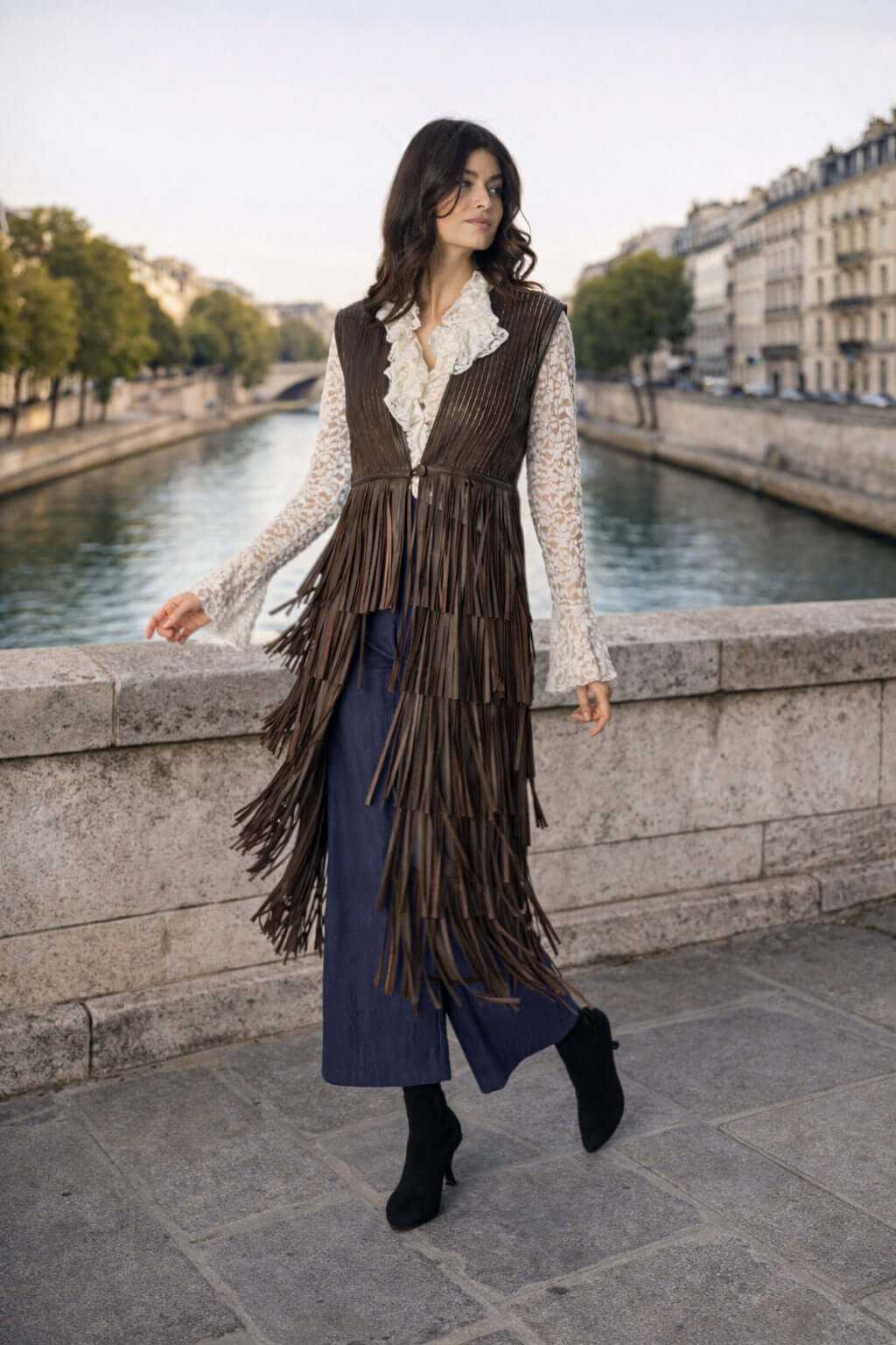 DIAMOND GILET indossato da una donna elegante, con frange, in un ambiente urbano vicino all'acqua.