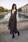 DIAMOND GILET indossato da una donna elegante, con frange, in un ambiente urbano vicino all'acqua.